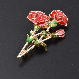 Detail of carnation brooch with red enamel petals, green rhinestones and golden stem