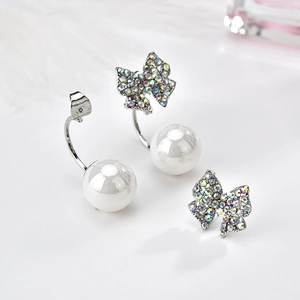 Dettaglio di orecchini a fiocco in argento con strass colorati e grandi perle