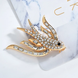 Detalle de broche de golondrina dorada con cristales brillantes y circonitas cúbicas