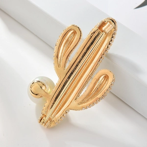 Elegante broche de cactus dorado con circonitas brillantes y perla blanca en blanco