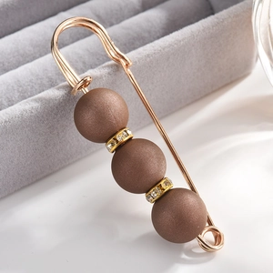 Macro view of a gold-tone brooch featuring matte brown beads and sparkling crystal rondelles