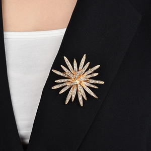 Close-up of a luxury gold sunflower brooch with sparkling rhinestones on a black suit lapel