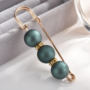 Macro detail of alloy brooch with matte dark green pearls and glittering rhinestones