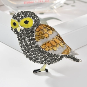 Détail d'une broche chouette avec strass gris et ailes en émail orange vif