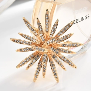 Macro detail of golden sunburst brooch with sparkling rhinestones on a white surface