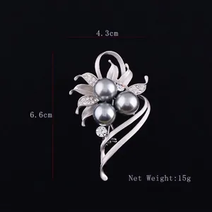 Elegant matte silver flower brooch with grey pearls and crystals on a black background