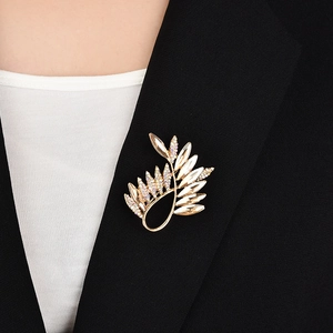 Détail d'une élégante broche feuille dorée en cristal sur une veste de costume noire