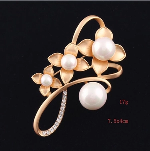 Detailed macro view of matte gold floral brooch with white pearls and sparkling rhinestones