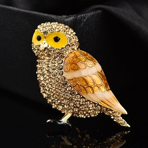 Vue macro d'une broche hibou avec cristaux champagne et détails fins en émail jaune