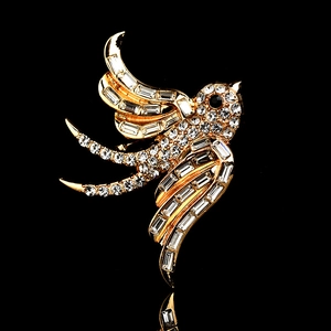 Elegante broche de golondrina dorada con cristales blancos en fondo negro reflectante