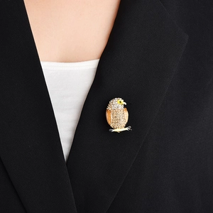 Détail d'une broche hibou en cristaux champagne sur le revers d'un blazer noir chic
