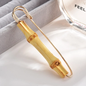 Detailed view of a gold bamboo-shaped brooch placed on a grey velvet jewelry box