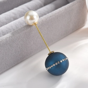 Detailed close-up of crystal rhinestone brooch with navy matte bead and cream pearl pin