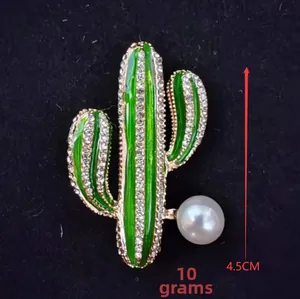 Macro detail of cactus brooch with green enamel, sparkling rhinestones and white pearl