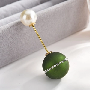 Detail of elegant gold brooch with white pearl and green rhinestone-encrusted matte bead