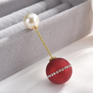 Detail of elegant gold brooch with a white pearl and red frosted bead with crystals