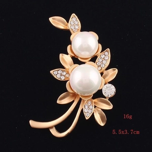 Elegant gold flower brooch with shell pearls and rhinestones on black background