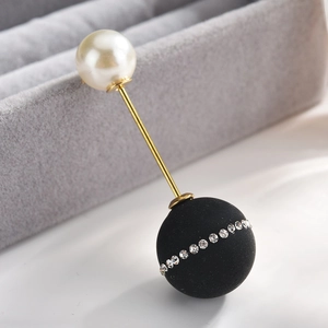 Detailed macro view of the gold alloy long pin brooch with a white pearl and rhinestone ball
