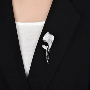 Détail d'une broche calla en argent sertie de zircones sur une veste de costume noire
