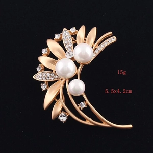Detail of matte gold floral brooch with white pearls and sparkling rhinestones