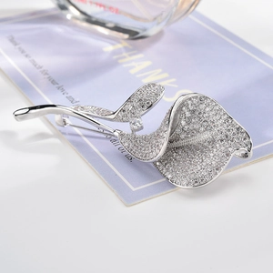 Détail de la broche fleur de calla en argent sertie de zircons sur fond couleur lavande