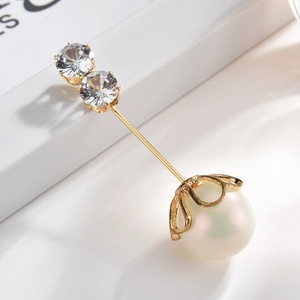 Detailed view of the dual rhinestone and white pearl pin with a polished gold finish