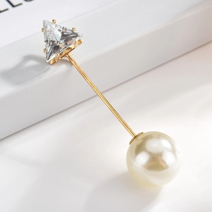 Detailed close-up of a long gold lapel pin featuring a triangle zircon and large pearl