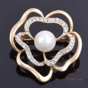 Macro shot of 3.5cm gold-toned camellia brooch with central pearl and rhinestone petals