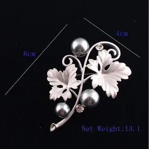Matte silver flower brooch with dark grey pearls and crystals on a dark background