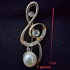 Detail view of a 5.2cm treble clef brooch with rhinestones and a large pearl