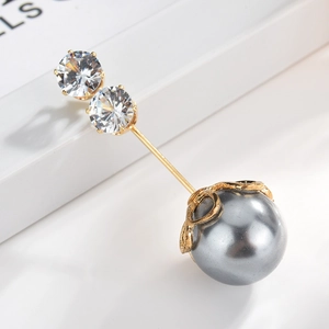 Detail of elegant gold brooch featuring a dark grey pearl and sparkling round zircons