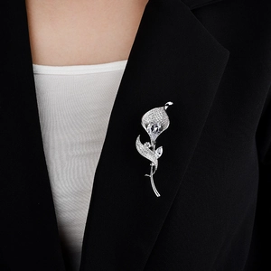 Detail of silver calla lily brooch with zircon pavé and large heart crystal on a blazer