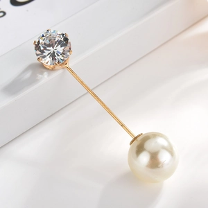 Detail of elegant gold pin featuring a white pearl and a clear faceted crystal