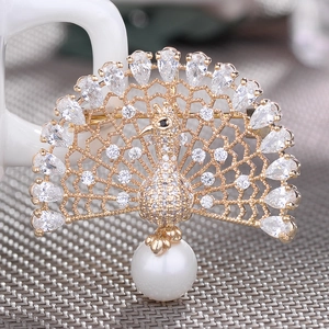 Macro shot of gold peacock brooch with zircon crystals and large round pearl pendant