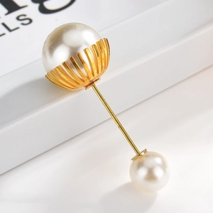 Macro detail of elegant gold-plated brooch with two white pearls and radial pattern