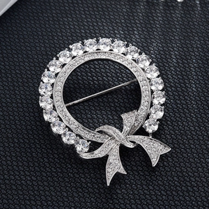 Vue détaillée d'une broche couronne argentée avec zircons et nœud sur tissu noir