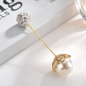 Close-up of elegant gold pin with white faux pearl and sparkling rhinestone ball