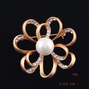 Detail view of flower brooch with matte gold finish, white pearl and crystal accents