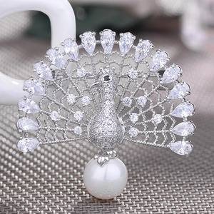 Detailed view of silver peacock brooch with pavé zircon stones and a large pearl drop