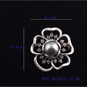 Detailed view of silver flower brooch with dark pearl and crystals measuring 4.5cm