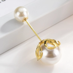 Detail of elegant gold brooch with dual pearls and designer style emblem on white stand