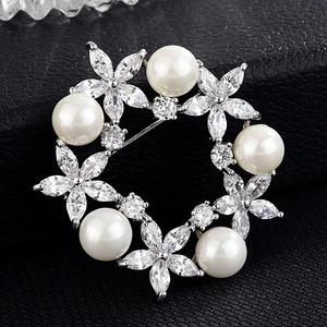 Détail de la broche ronde en perles avec fleurs en zircon sur fond en cuir noir élégant