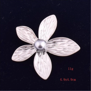 Macro detail of silver flower brooch with shell pearl and radial petal textures