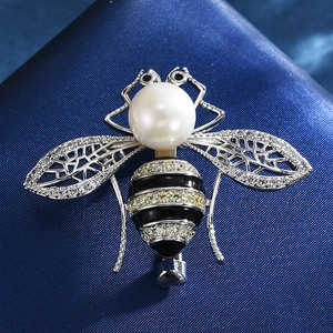 Makroaufnahme einer silbernen Bienenbrosche mit großer Perle, Zirkonia-Flügeln und Emaille