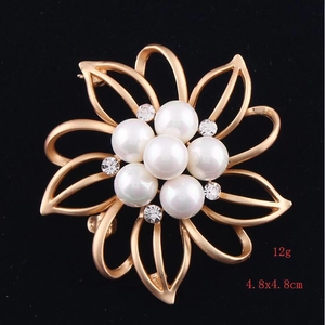 Detail view of flower brooch with gold alloy petals, 7 pearls and rhinestones on black base