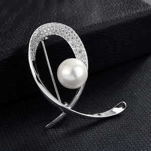 Vue macro d'une broche argentée élégante avec perle blanche et strass sur cuir noir