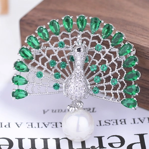 Macro detail of luxury peacock brooch with green zircons and a large white pearl drop