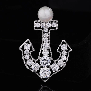 Macro shot of anchor brooch with inlaid crystals and a white pearl on black velvet