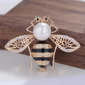 Eleganter Gold-Bienen-Brosche mit Perlenkopf und Zirkonia-Flügeln auf dunklem Holz