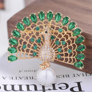 Macro detail of elegant peacock brooch featuring green gems, white zircon and a pearl drop